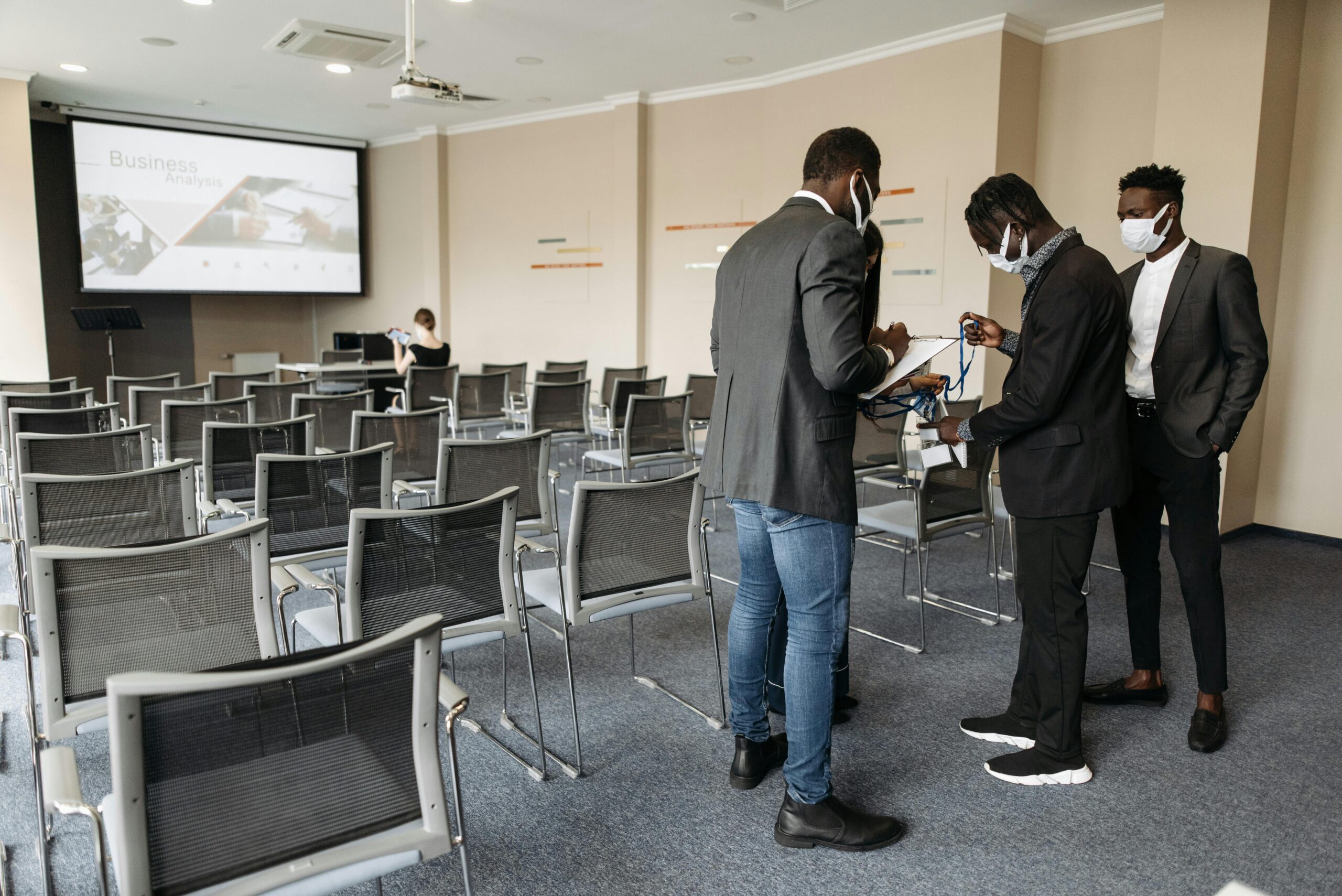 Group of professionals in a conference room adhering to safety protocols during a presentation.